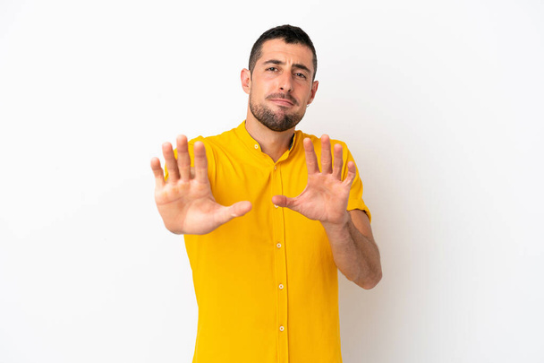 Молодой красивый кавказский мужчина на белом фоне нервно вытянув руки на передний план - Фото, изображение