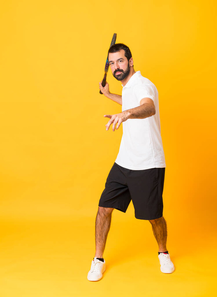 Повнометражний знімок людини над ізольованим жовтим тлом, граючи в теніс
 - Фото, зображення