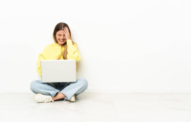 Young woman with a laptop sitting on the floor smiling a lot - Photo, Image