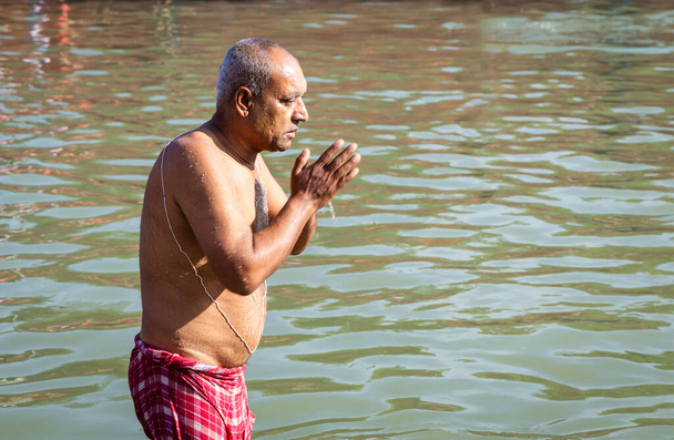 відданий молиться після купання в священній річковій воді вранці з плоского кута - Фото, зображення