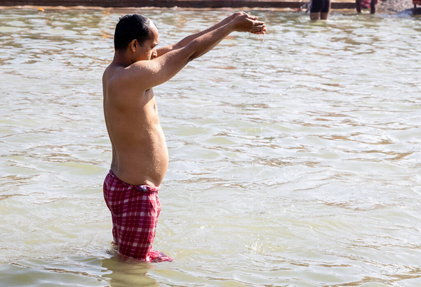 молодий відданий молиться за святого бога після купання у святій річковій воді з ранку під рівним кутом - Фото, зображення