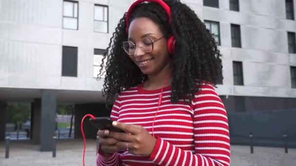Beautiful black woman with headphones listening to music. Happy shopping online with cell phone for easy and secure remote electronic payments.  - Footage, Video