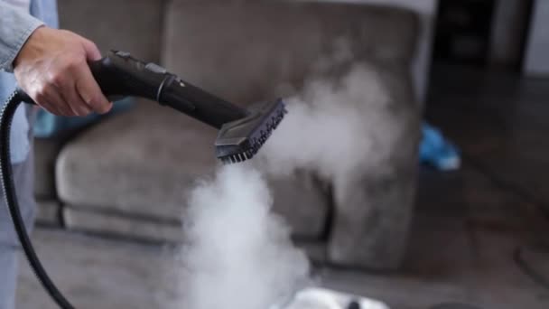 House cleaning. A man cleans the sofa and furniture with a steam generator. Cleaning service of the apartment. flat la. Strong vapor pressure. - Footage, Video