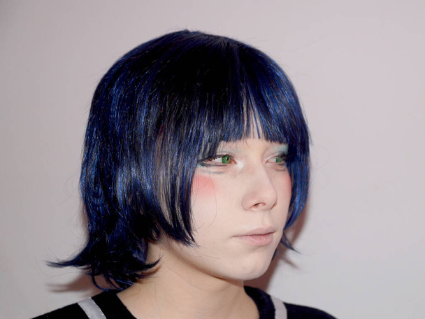 portrait of a sad teenage girl in anime style with blue hair and green eyes, side view - Photo, Image