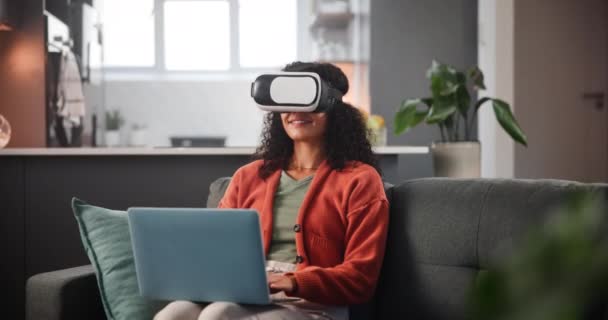 VR, kobieta i zestaw słuchawkowy na sofie z laptopem do interaktywnej metawersji, rozszerzony świat i uśmiech. Okulary 3D, osoba i futurystyczna technologia z cyfrowymi innowacjami, wirtualną rzeczywistością i relaksem w domu. - Materiał filmowy, wideo