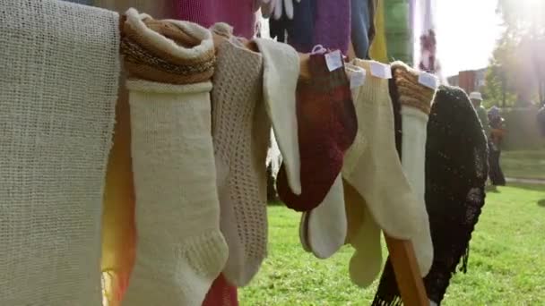 Gebreide sokken, sjaals en handschoenen hangend op de stand op de artisanale markt. Breien is een methode voor de productie van textiel door garen lussen met lussen van dezelfde of andere garens met elkaar te verbinden. - Video