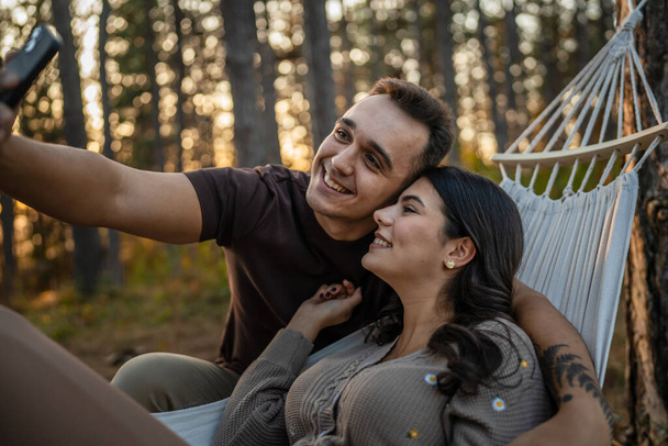Muž a žena mladý dospělý pár v přírodě vzít autoportrét fotografie selfie ugc použít mobilní telefon smartphone nebo video hovor - Fotografie, Obrázek