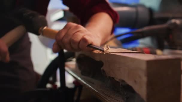 Τεχνίτης σκάλισμα σε ξύλο χρησιμοποιώντας σμίλη και σφυρί σε ξυλουργείο με ακρίβεια. Κατασκευαστής σε στούντιο διαμόρφωση ξύλινα κομμάτια με εργαλεία, καθιστώντας την τέχνη του ξύλου, κάμερα B κοντινό πλάνο - Πλάνα, βίντεο