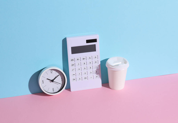 White calculator with clock and coffee cup on blue-pink background with shadow. Business and finance concept. Creative mockup - Photo, Image