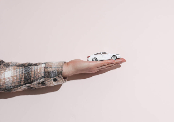 Férfi kéz a pólóban tartó játék autó bézs háttér árnyék - Fotó, kép