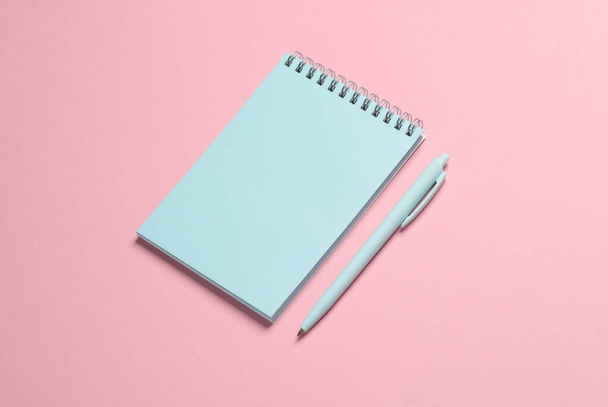 Niebieski zeszyt z długopisem na różowym tle. Minimalizm - Zdjęcie, obraz
