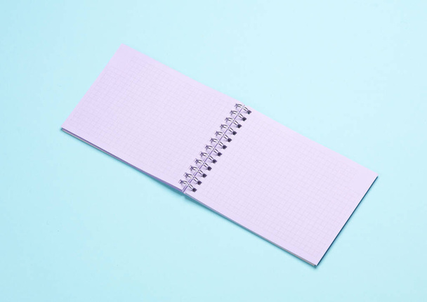 Open purple pastel notebook on blue background - Photo, Image