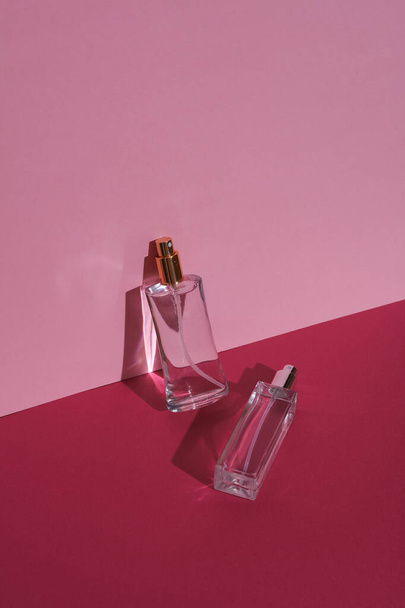 Parfumflesjes op een roze achtergrond met schaduw. Schoonheidsconcept. Creatieve lay-out, minimalisme - Foto, afbeelding