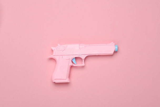 Plastic pistol on a pink background. Minimalism - Photo, Image
