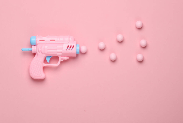 Pistola de plástico con bolas sobre fondo rosa. Diseño creativo. Minimalismo - Foto, imagen