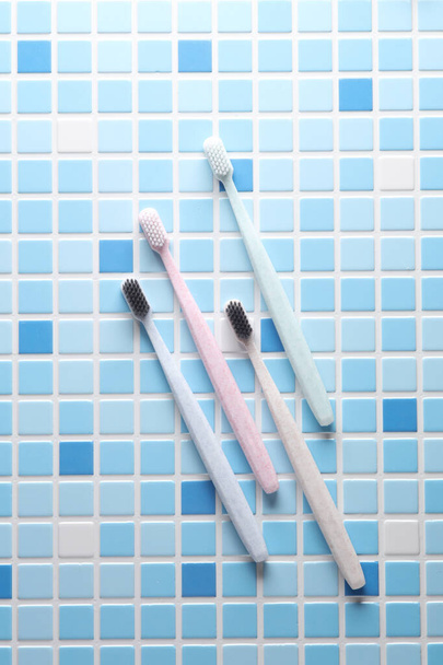 Cepillos de dientes de plástico en una baldosa azul. Vista superior - Foto, Imagen