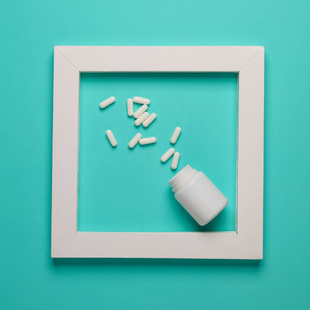 Frasco de pastillas en marco blanco sobre fondo azul. Diseño creativo. Minimalismo - Foto, Imagen
