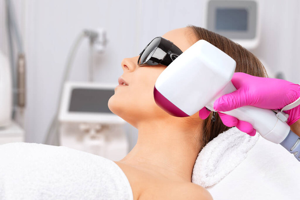 epilation hair removal procedure on a womans body. Beautician doing laser rejuvenation in a beauty salon. Removing unwanted body hair. Hardware ipl cosmetology - Photo, Image