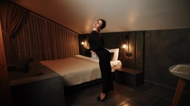 Elegante donna in un abito nero in posa in un appartamento.Donna in un abito nero e labbra rosse in posa per la fotocamera Fashion shooting concept 4K - Filmati, video