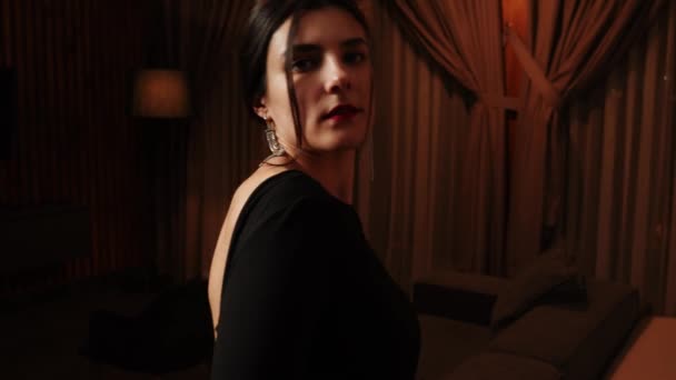 Elegante Frau im schwarzen Kleid posiert in einer Wohnung.Frau im schwarzen Kleid und roten Lippen posiert für die Kamera - Filmmaterial, Video