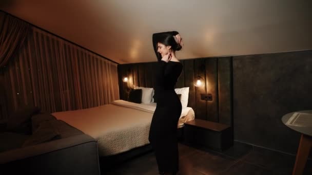 Элегантная женщина в черном платье позирует в квартире. Женщина в черном платье и красные губы позируют для камеры - Кадры, видео