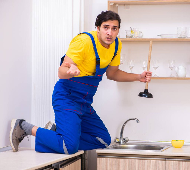 Ο νεαρός εργολήπτης επισκευάζει κλακέτες στο σπίτι - Φωτογραφία, εικόνα