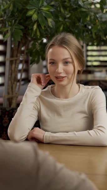beautiful woman having meeting in cafe, looking at camera, speaking. Young woman has lunch at restaurant. Vertical view - Footage, Video
