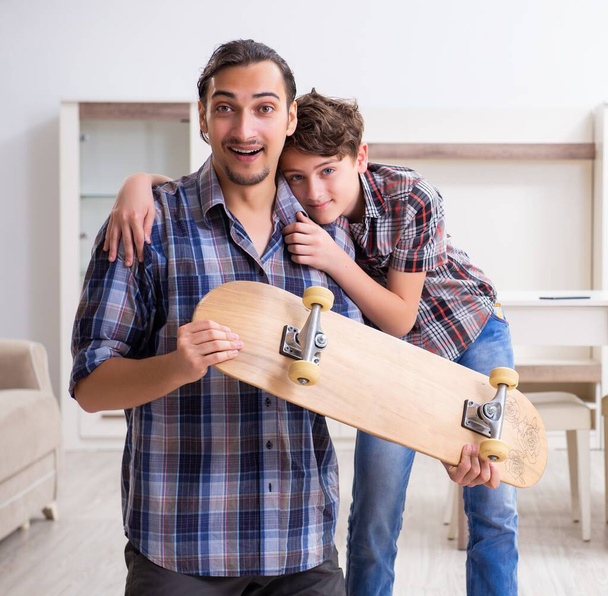 Der junge Vater repariert mit seinem Sohn zu Hause Skateboards - Foto, Bild