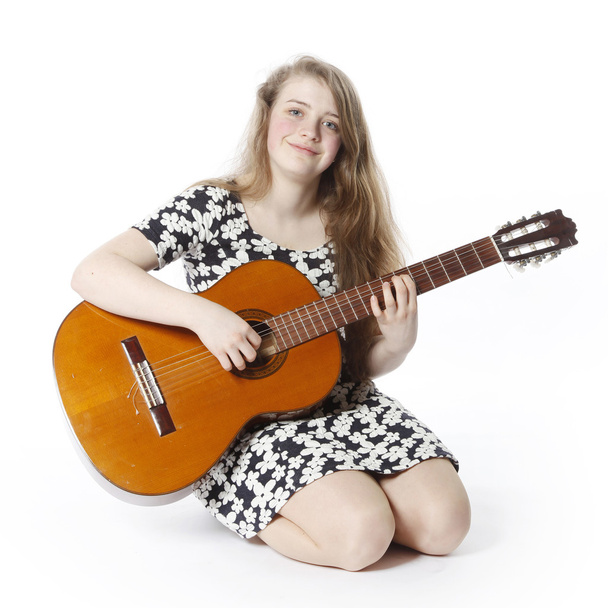 smiling teenage girl in dress plays the guitar in studi - Fotó, kép