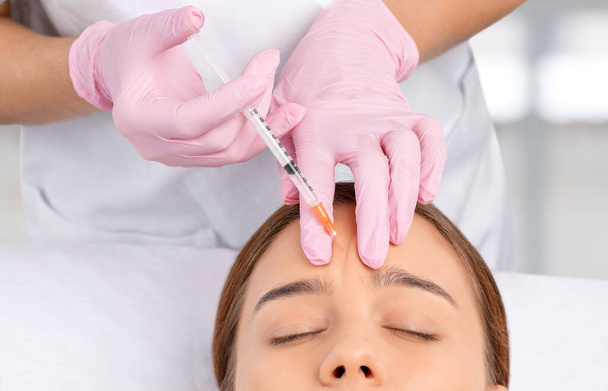 El cosmetólogo hace rejuvenecedoras inyecciones antiarrugas en la cara de una mujer hermosa. Cosmetología estética femenina en un salón de belleza. - Foto, imagen