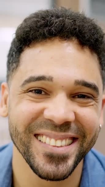 Κάθετη αργή κίνηση βίντεο ενός ευτυχισμένου ισπανόφωνου άνδρα χαμογελώντας στην κάμερα που εργάζεται σε ένα coworking - Πλάνα, βίντεο