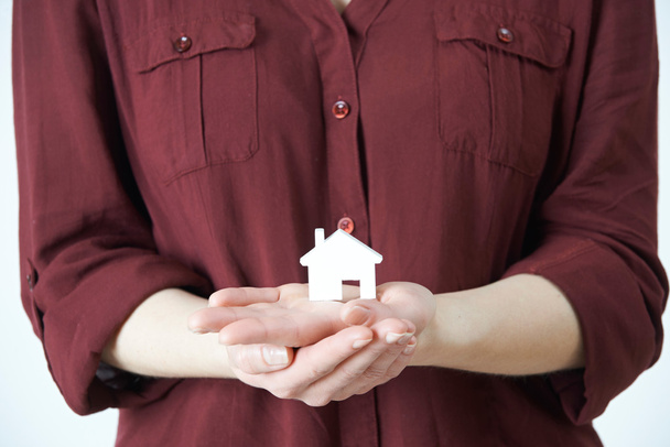Mujer sosteniendo la casa modelo en palma de la mano
 - Foto, Imagen