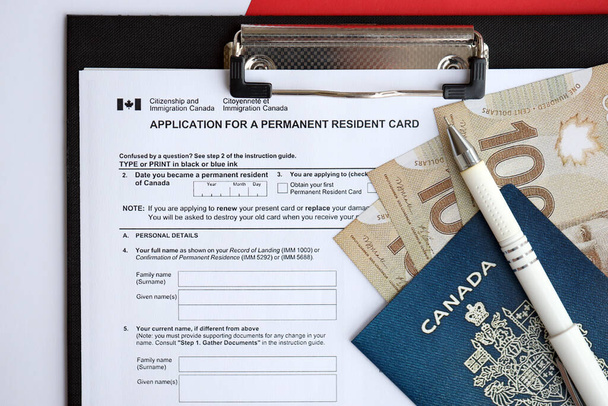 Заява на посвідчення особи на столі з ручкою і канадським паспортом з грошима крупним планом - Фото, зображення