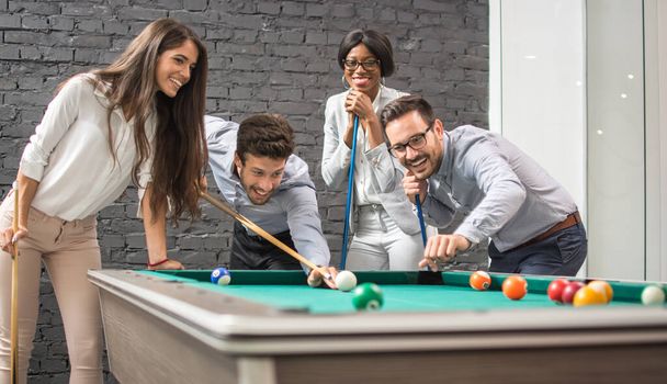Cheerful business people playing billiards during office break. - Photo, Image