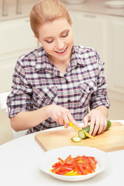 Woman cuts cucumber and pepper - Foto, imagen