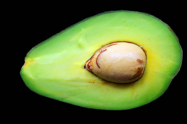 Ripe avocado cut in half with large seed inside ideal as a concept of healthy eating and well-being - Photo, Image
