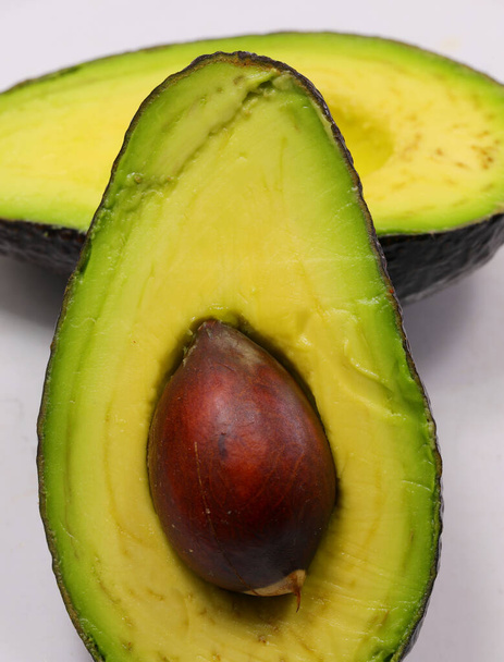 Halbierte Avocado mit großem Samen innen, ideal als gesundes Ess- und Wellness-Konzept auf weißem Hintergrund - Foto, Bild
