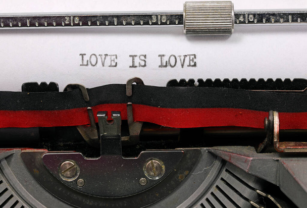 LOVE IS LOVE handwritten in black ink on white paper with an antique typewriter symbolizing universal and boundless love - Photo, Image