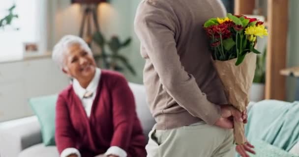 Старий чоловік, жінка і сюрприз квіткового букета на дивані, щасливий і пара у вітальні будинку. Старший, чоловік і партнер з подарунком на любов, посмішку і щастя вдома і на пенсії. - Кадри, відео