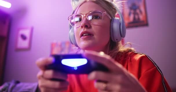 Fejhallgató, boldog nő és játszani videojáték otthon a verseny és az online rpg. Vezérlő, lány és mosoly személy konzol technológia szórakoztató neon fény lakásban éjjel. - Felvétel, videó