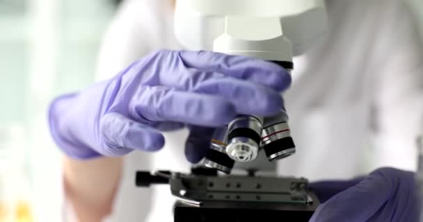 Laboratorion tiedemies katsoo mikroskooppia, lähikuvan käsiä. Kemialliset tutkimuslaitteet - Materiaali, video