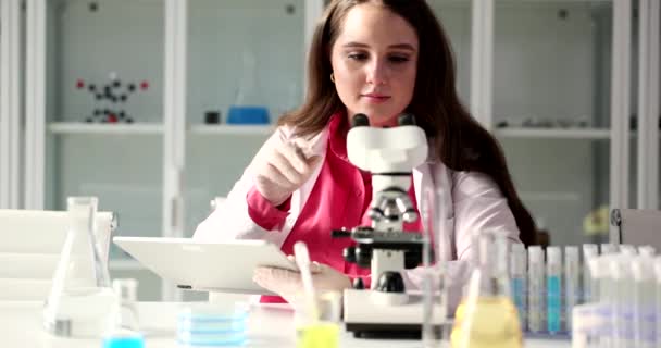 Krásná dívka se dívá na mikroskop v laboratoři, zblízka. Vývoj, vědecký výzkum - Záběry, video