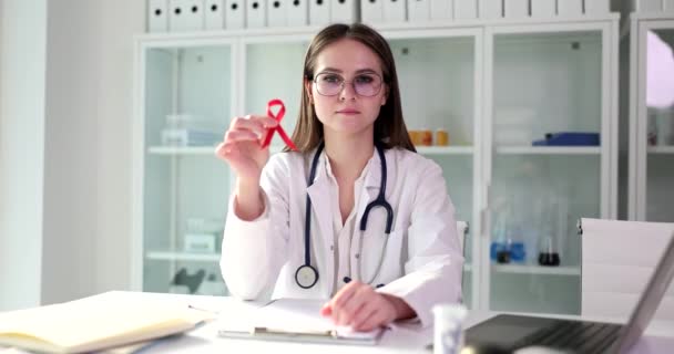 Die junge Ärztin hält ein rotes Band in der Hand, das Brustkrebs symbolisiert, eine Nahaufnahme. Gesundheitsdiagnostik, Mammographie - Filmmaterial, Video