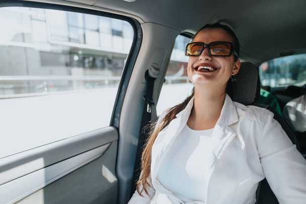 Magabiztos női ügyvezető, akit autóval visznek egy vállalati találkozóra, bemutatva a mobilitást és a városi üzleti életmódot. - Fotó, kép