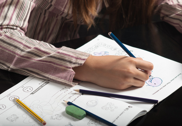 Teenage girls hand holding pencil and doing her homework. - Foto, imagen