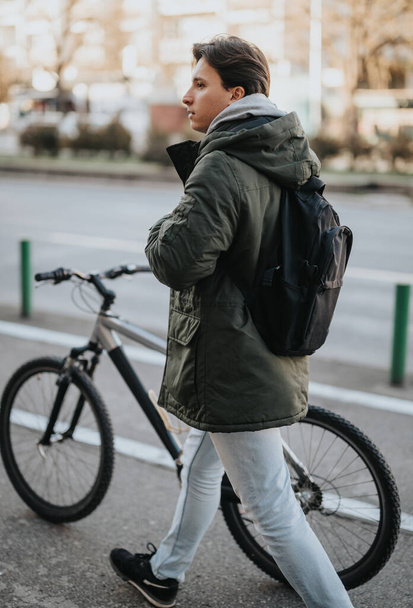 Jovem adulto com uma mochila andando ao lado de uma bicicleta em uma rua da cidade, exalando um senso de estilo de vida urbano e mobilidade. - Foto, Imagem