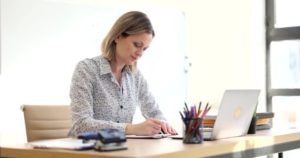 Una joven empresaria escribe sentada en una mesa en la oficina, un primer plano. Lugar de trabajo de la cabeza, carrera - Metraje, vídeo