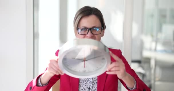 Happy business woman in the office holds a big wall clock, a close-up. Successful start of the working day - Footage, Video