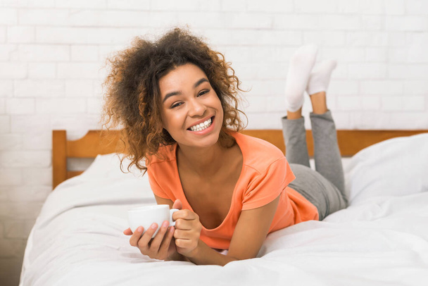 Happy woman enjoying cup of coffee in bed in the morning - Photo, Image