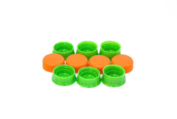 Several green and orange color plastic bottle caps isolated on white background. - Photo, Image